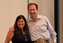 Chris Todd, the new CEO of UKG, is presented with a champion belt by Jennifer Brafman Staffen of UKG Corporate Communications during a June 2022 Analyst Relations event in Fort Lauderdale, FL