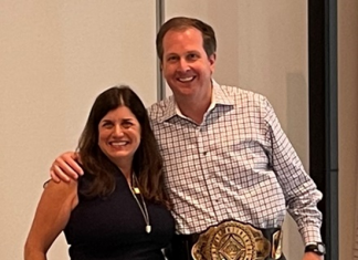 Chris Todd, the new CEO of UKG, is presented with a champion belt by Jennifer Brafman Staffen of UKG Corporate Communications during a June 2022 Analyst Relations event in Fort Lauderdale, FL